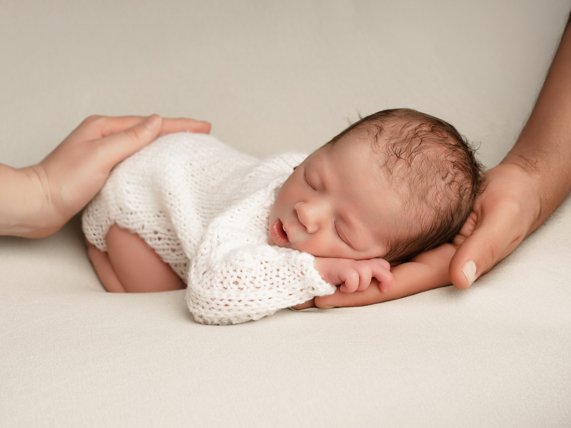 Nouveau-né dormant paisiblement sur un fond blanc épuré lors d'une séance photo minimaliste à Mende