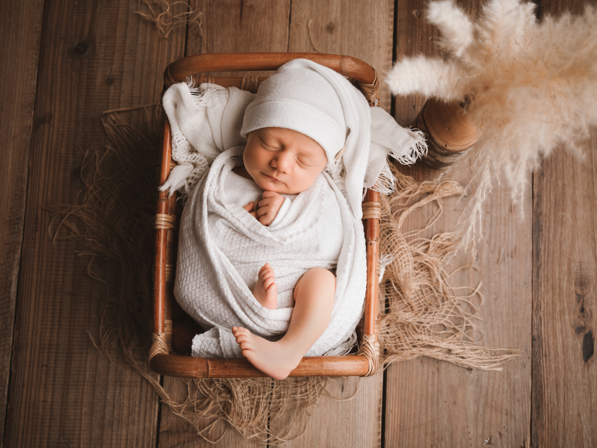 Petit bébé paisiblement endormi dans un petit lit en bois lors d'une séance photo de naissance à Mende