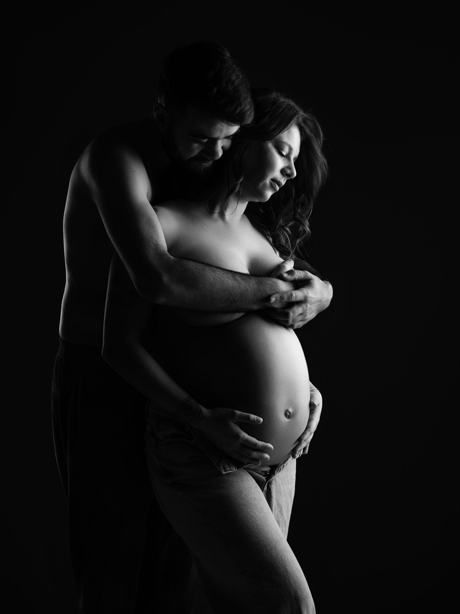 Portrait original d'un couple attendant un enfant, mis en valeur par des lumières intimistes en studio en Lozère