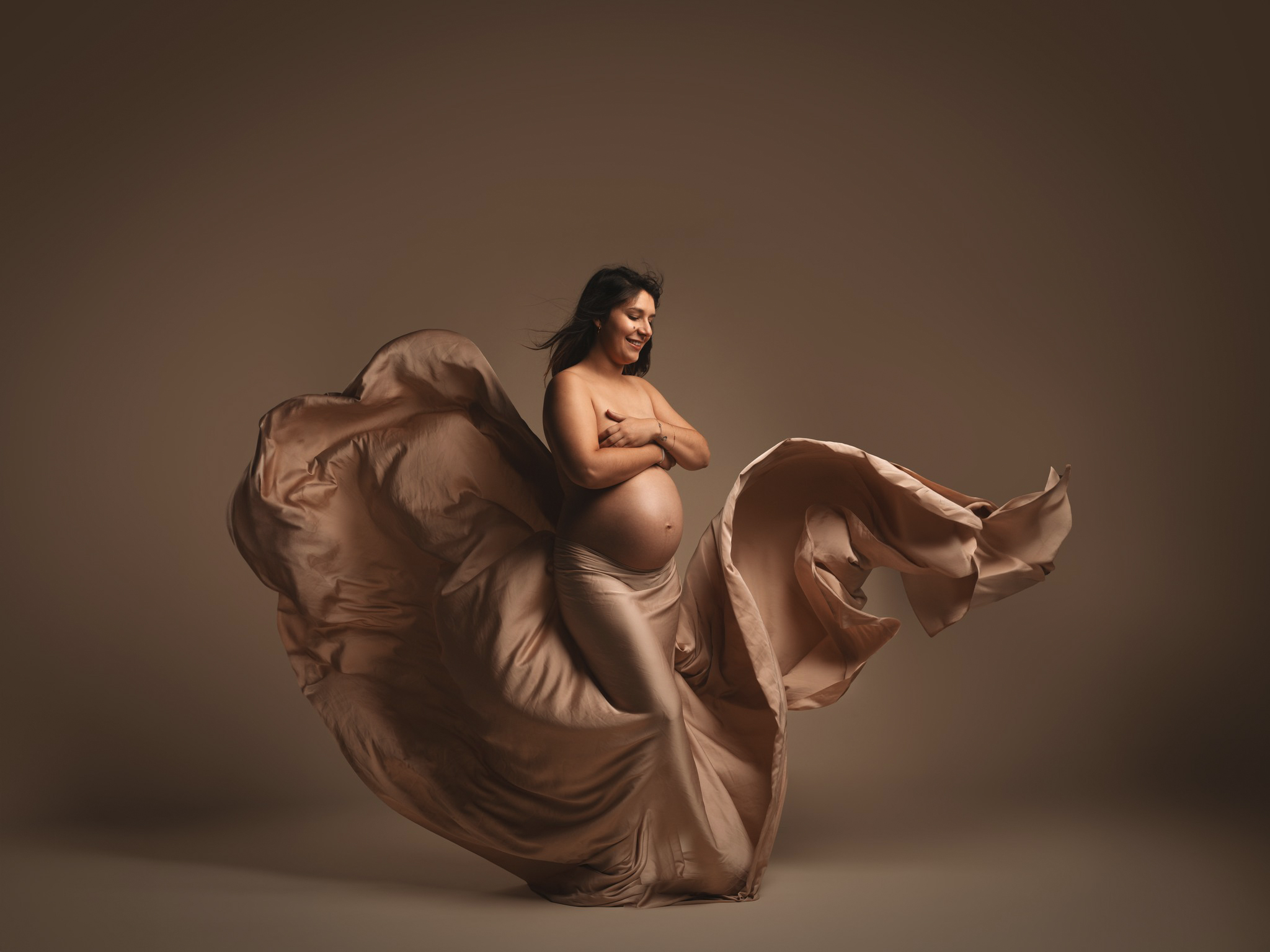 Le futur papa créant du mouvement avec un grand drapé volant derrière la femme enceinte en studio à Mende