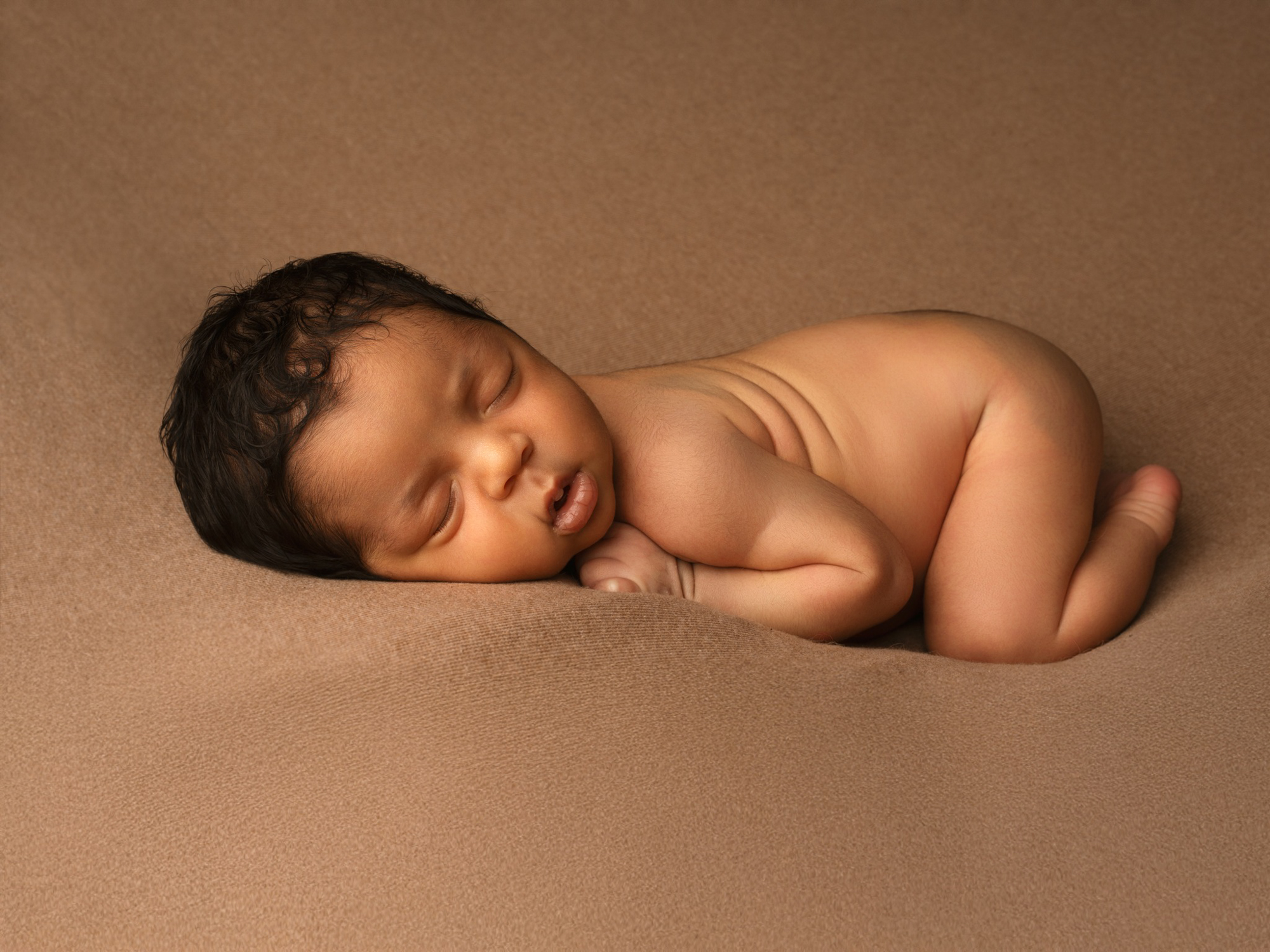 Gros plan sur les traits délicats d'un nouveau-né photographié sur un fond marron doux à Mende