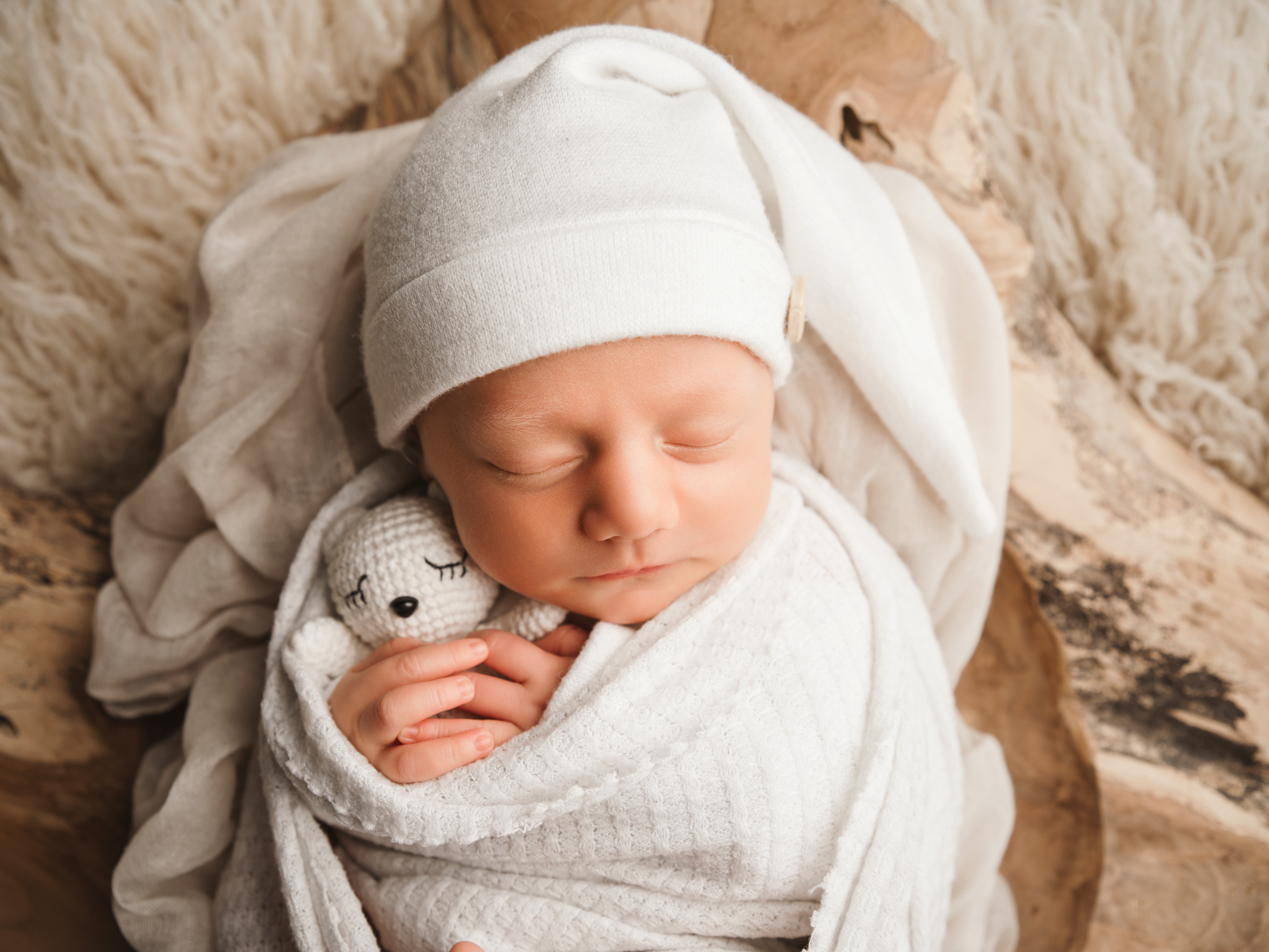 Gros plan d'un nouveau-né endormi sur un chaleureux fond en bois à Mende.