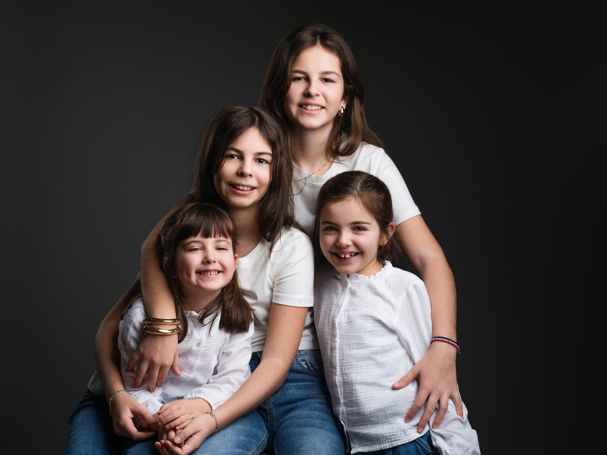 Famille souriante posant ensemble lors d'une séance photo sur fond noir épuré à Mende